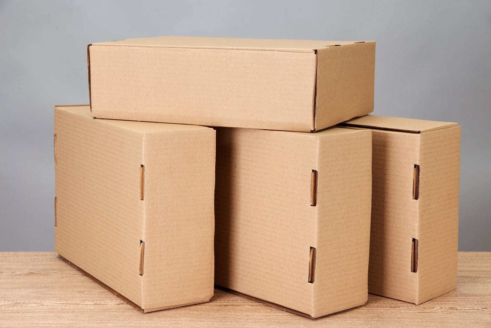 parcels-boxes-on-wooden-table-on-grey-background-min